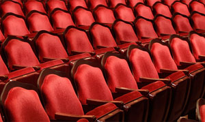 Empty red velvet seats of a theatre auditorium.
