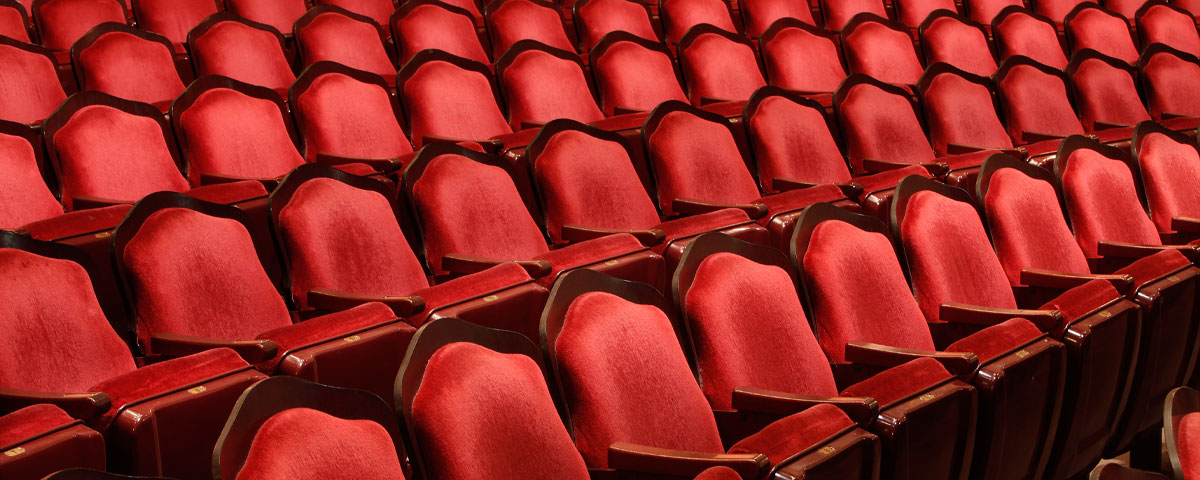 Empty red velvet seats of a theatre auditorium.