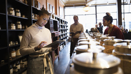 Shop assistant stood behind the counter looking at her computer