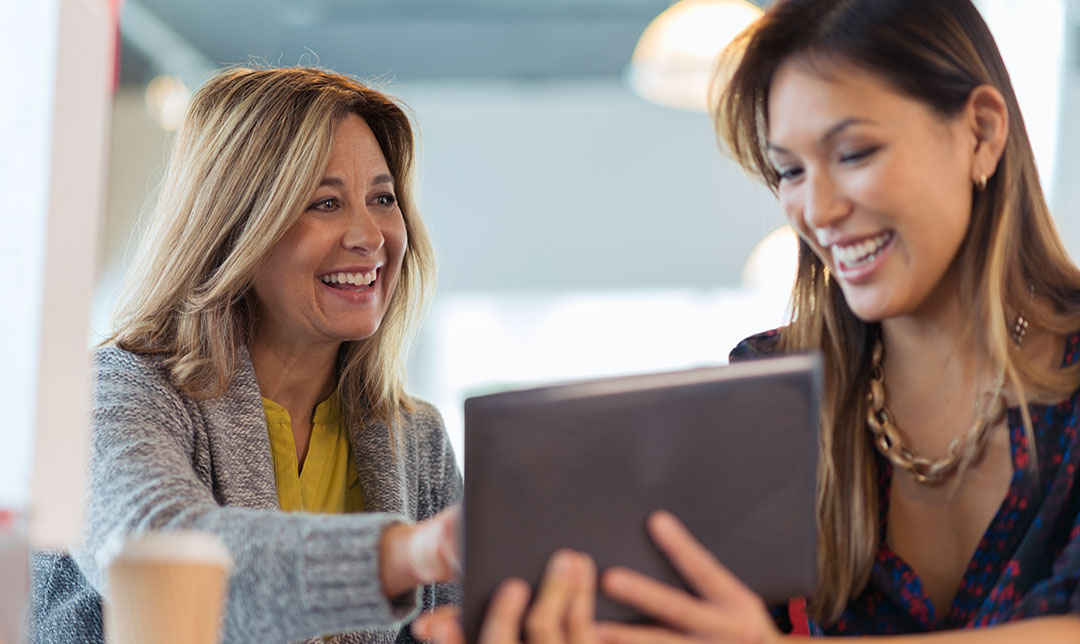 Two ladies looking at an Ipad smiling