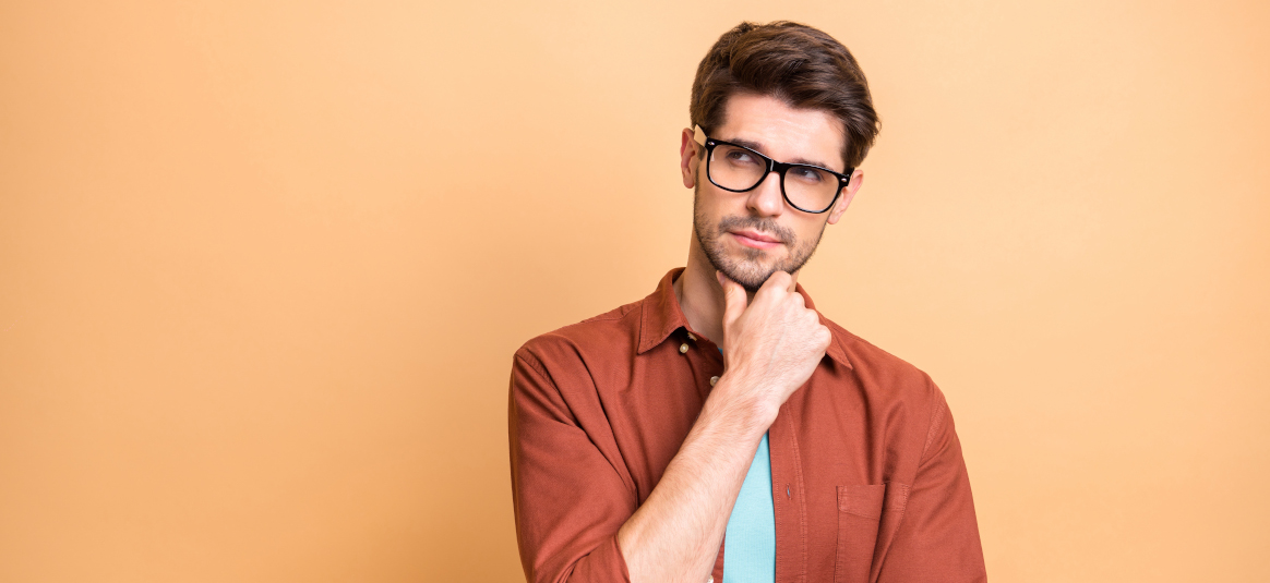 Photo of man with glasses thinking in front of an orange background