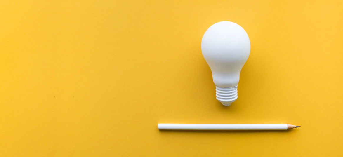 Photo of a white light bulb and pencil on a yellow background