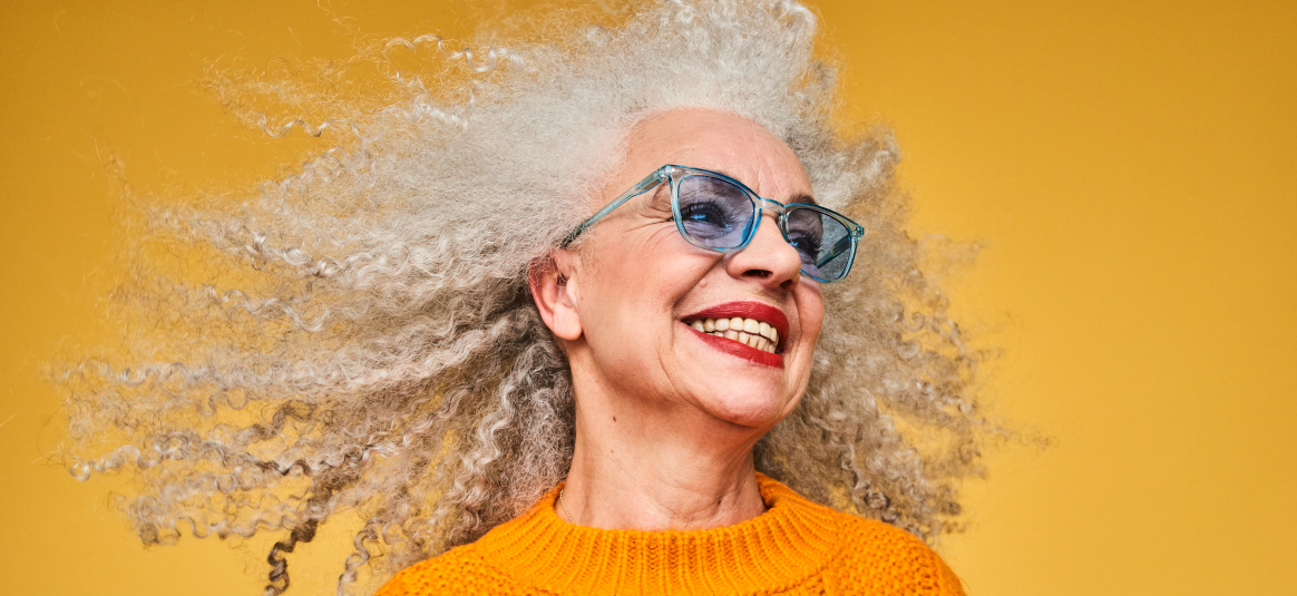 Photo of woman with glasses and streaming hair in front of a yellow background