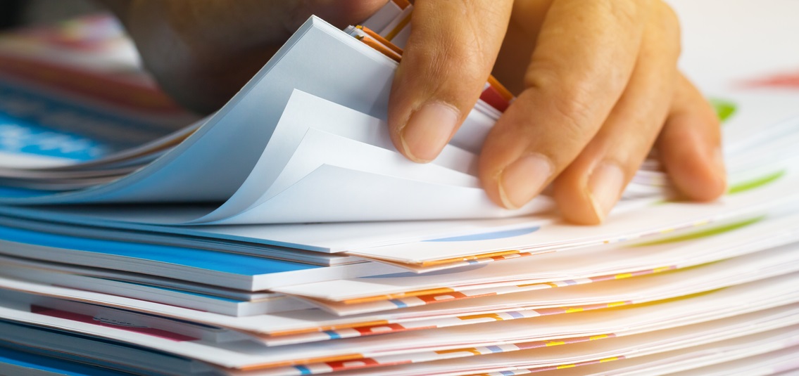 photo of hand leafing through a stack of documents