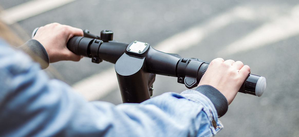 Close up of hands on the handlebars of an electric scooter 