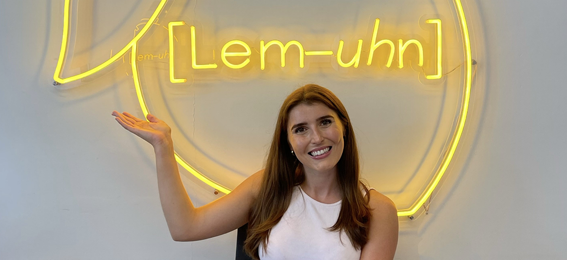 Photo of Riannon from lem uhn in front of neon company logo