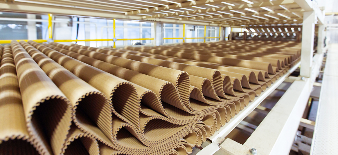 Corrigated cardboard being produced by a machine.