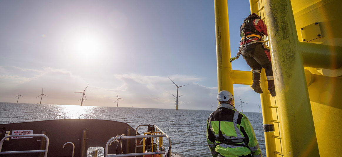Photo of workers doing maintenance work on a wind turbine out at sea