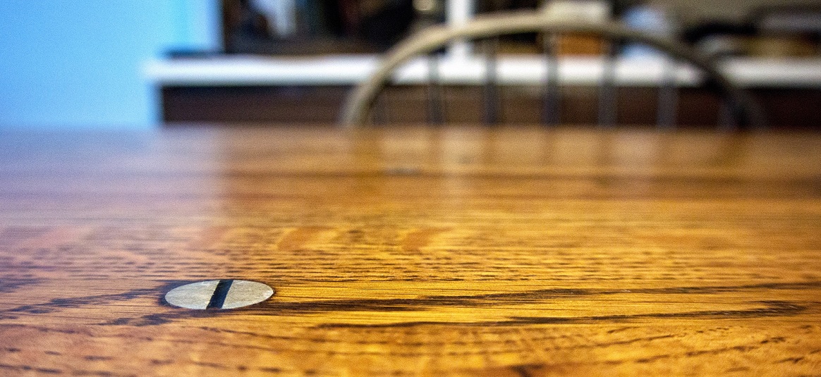 A close up of a screw on a wooden table top