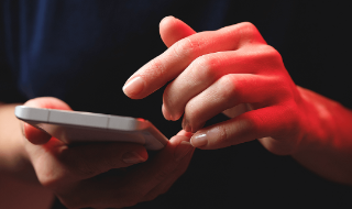 Hands hold and operate a smartphone.