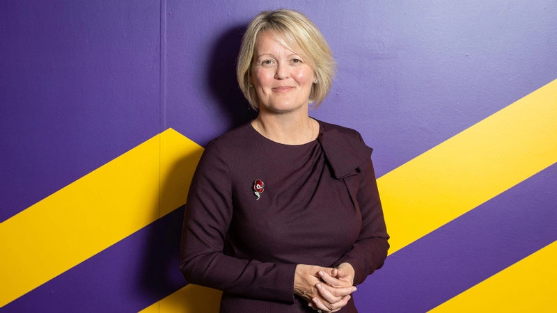Alison Rose in front of a purple and yellow wall