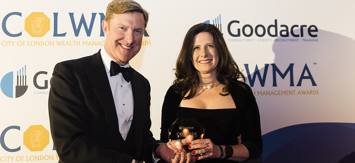 A man and a woman smiling at the camera and holding an award. 