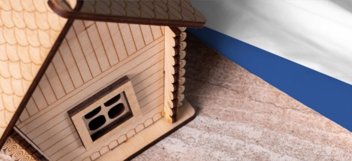 Dutch flag beside wooden log cabin model.