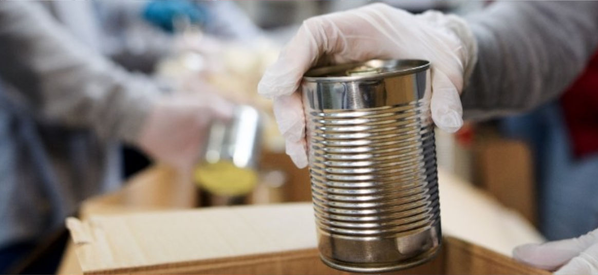 Hygiene-gloved hands hold an unlabelled aluminium food can. 