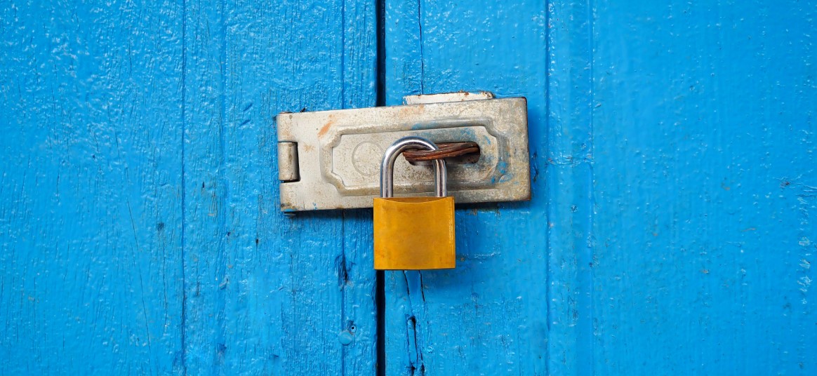 A locked padlock on a brightly coloured door