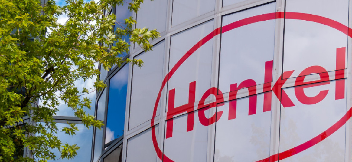 Large red lettering of Henkel logo, transferred onto white, opaque window glazing of building.