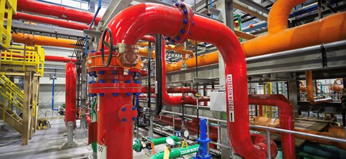 Interior, industrial-scale chlorine manufacturing plant, with brightly coloured steel pipes.