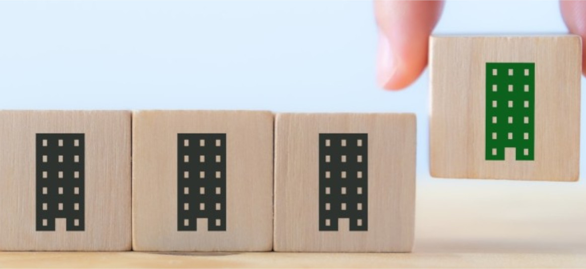 A hand moves a wooden cube with a green towerblock icons stencilled on it, beside a row of wooden cubes featuring black-coloured stencilled towerblocks.