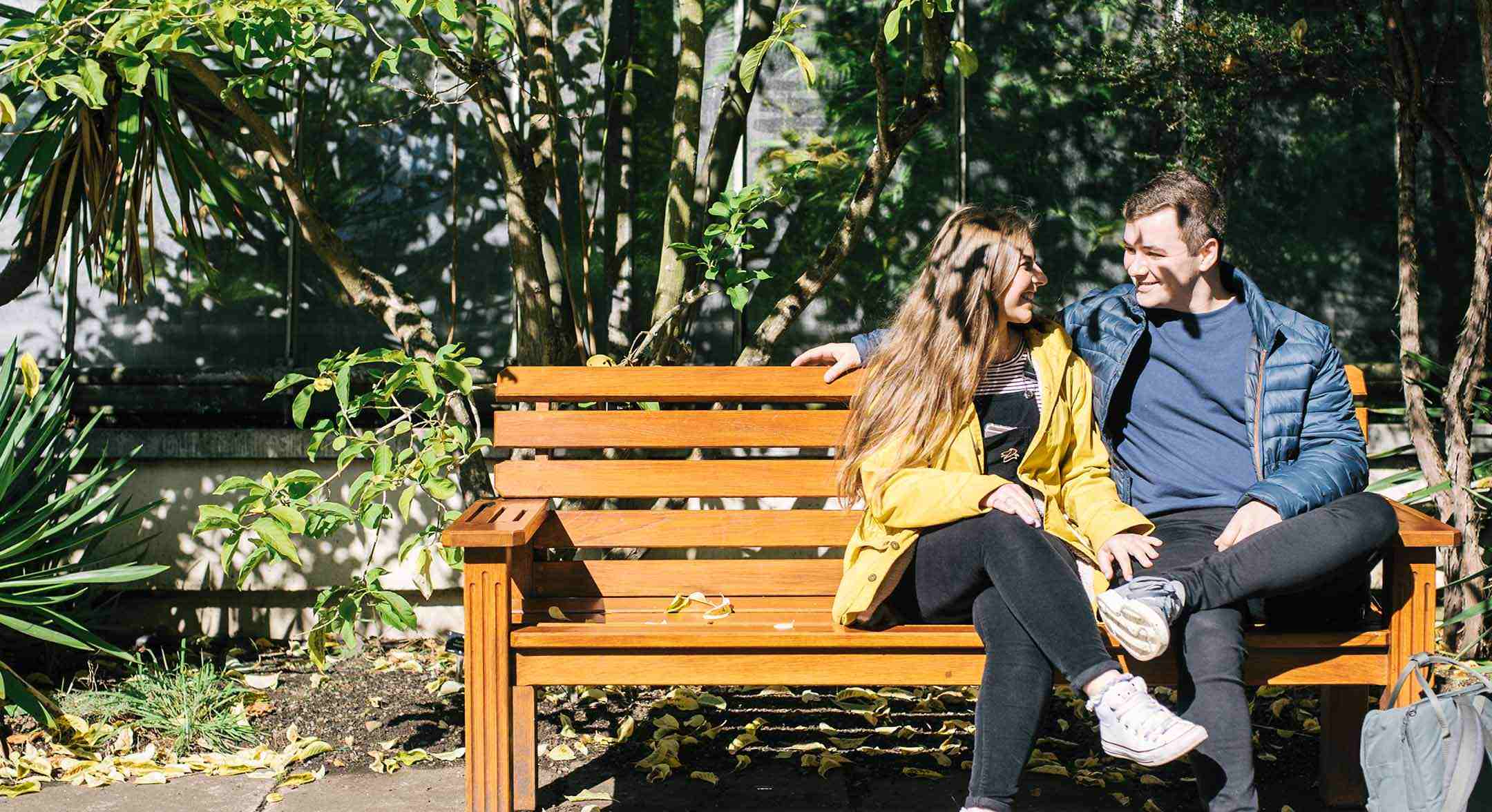 Boy and girl sitting on a bench in the sunshine