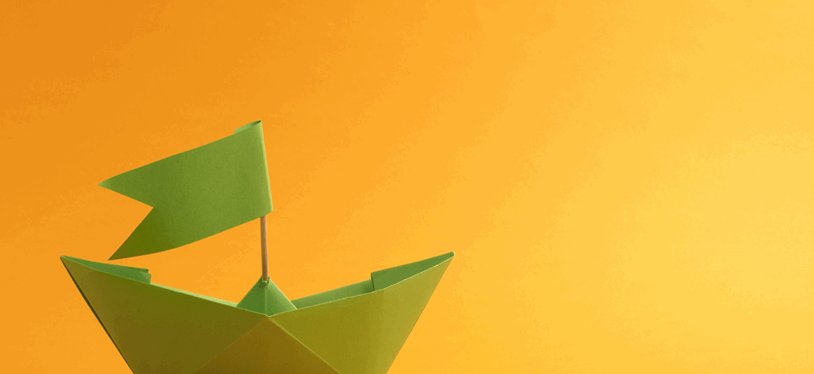 Green paper boat sails against an orange background.