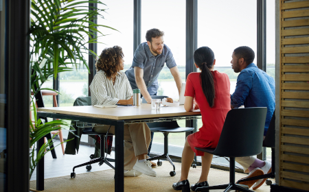 Four people sitting at a table in an office meeting room.