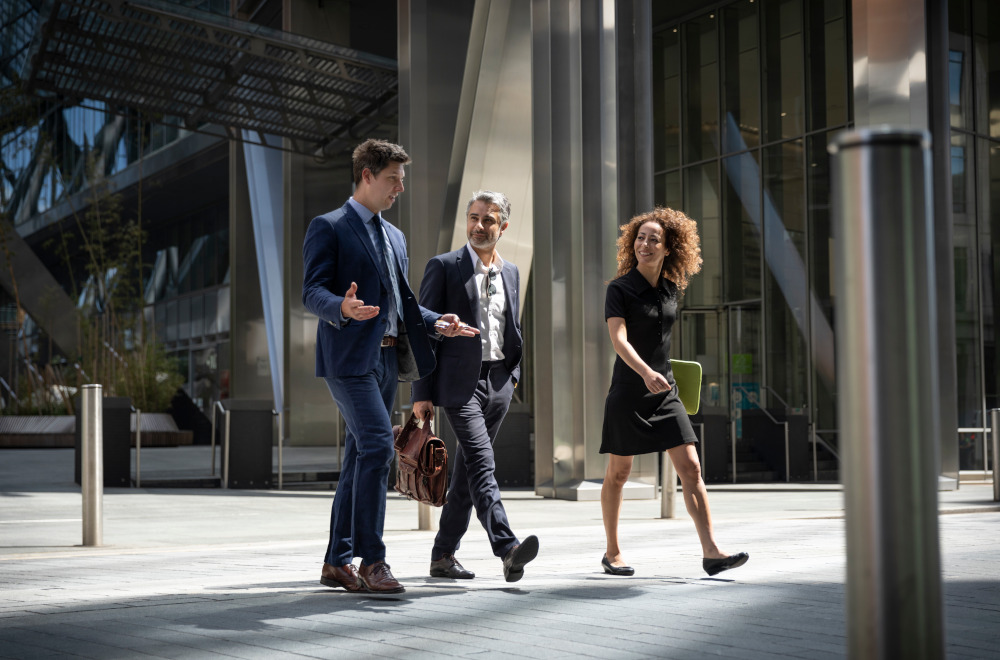 Business colleagues walking together and having a conversation outside a modern office building.