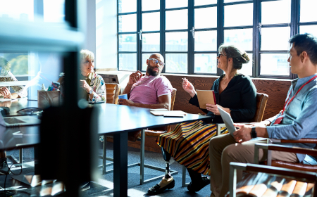 Four people in discussion sitting at an informal conference table.