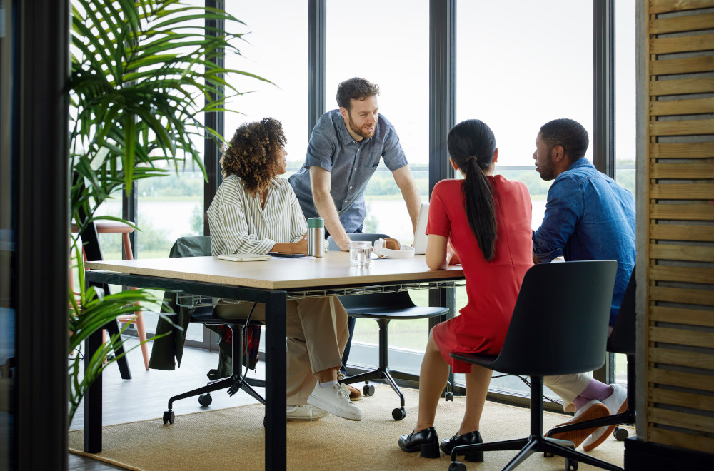 A group of four professionals talking to each other over a table in a modern looking office.