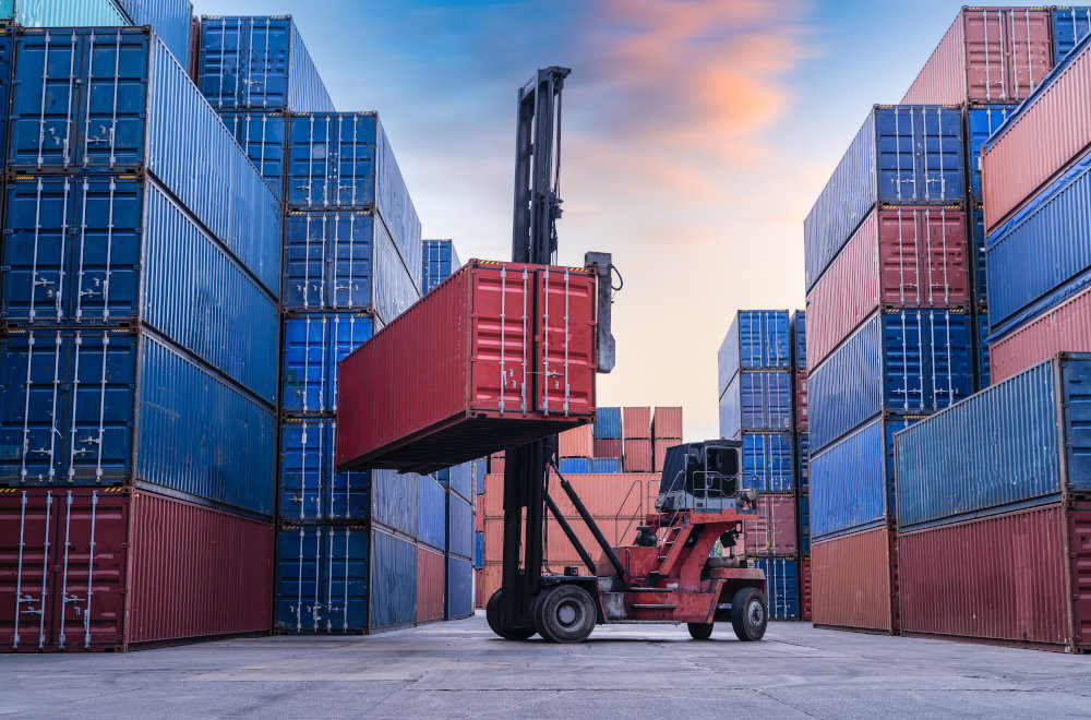 Port forklift hauling an shipping container onto a stack.