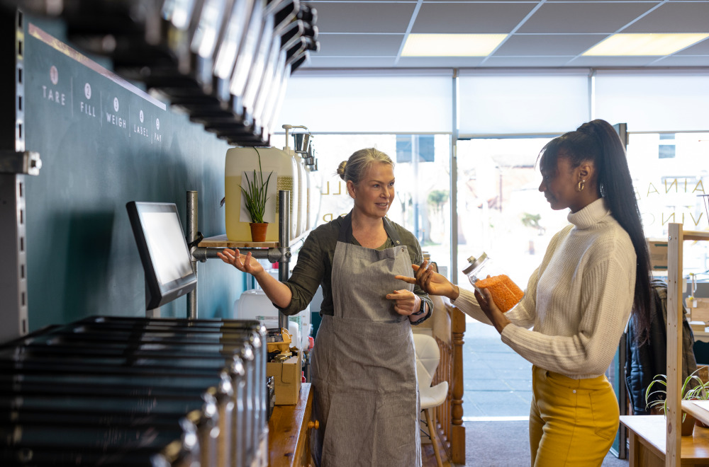 Two women standing at a modern looking self-checkout till.
