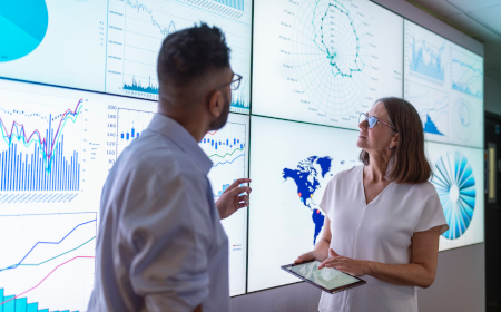 A man and a woman standing in an office looking at data projected onto a screen.