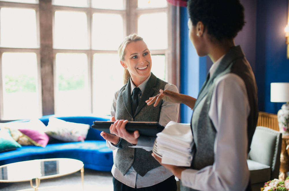 Two hospitality staff members conversing in a hotel setting, appearing engaged and professional.