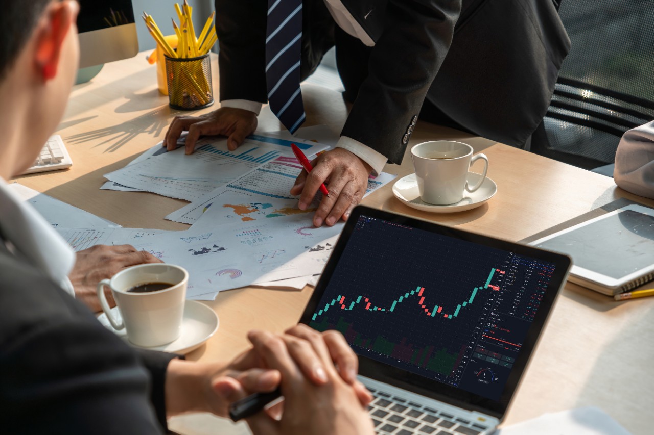 Man in a business suit looking at a financial data graph on a laptop.