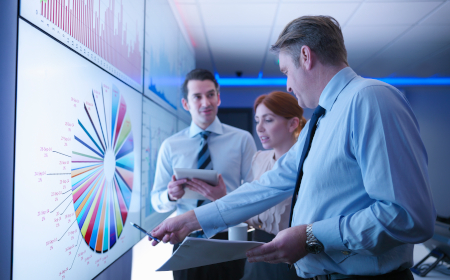 A group of professionals looking at data on a big screen.