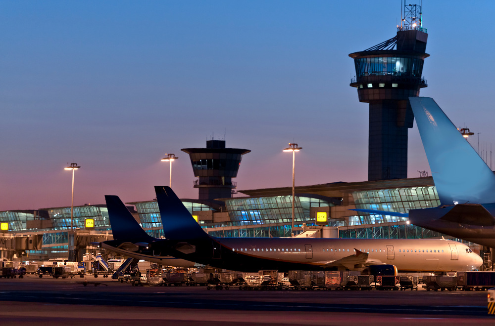 Planes parked at an airport terminal at dusk.