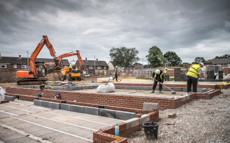 Construction workers in hi vis jackets building the foundations of a house.