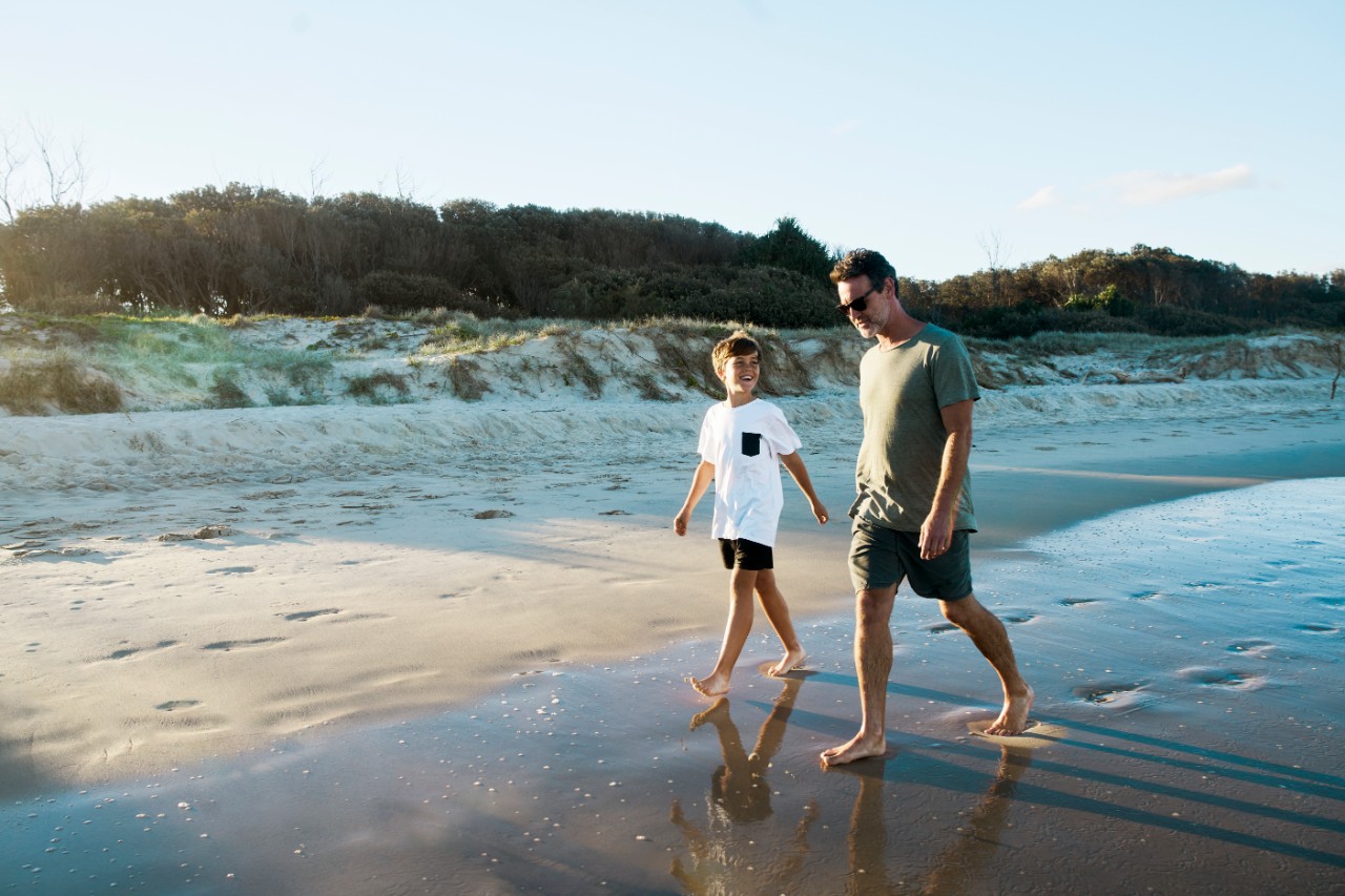 A NatWest Premier financial planning customer walks on the beach with his son