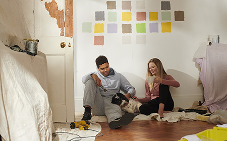 Couple sat on the floor after painting a wall