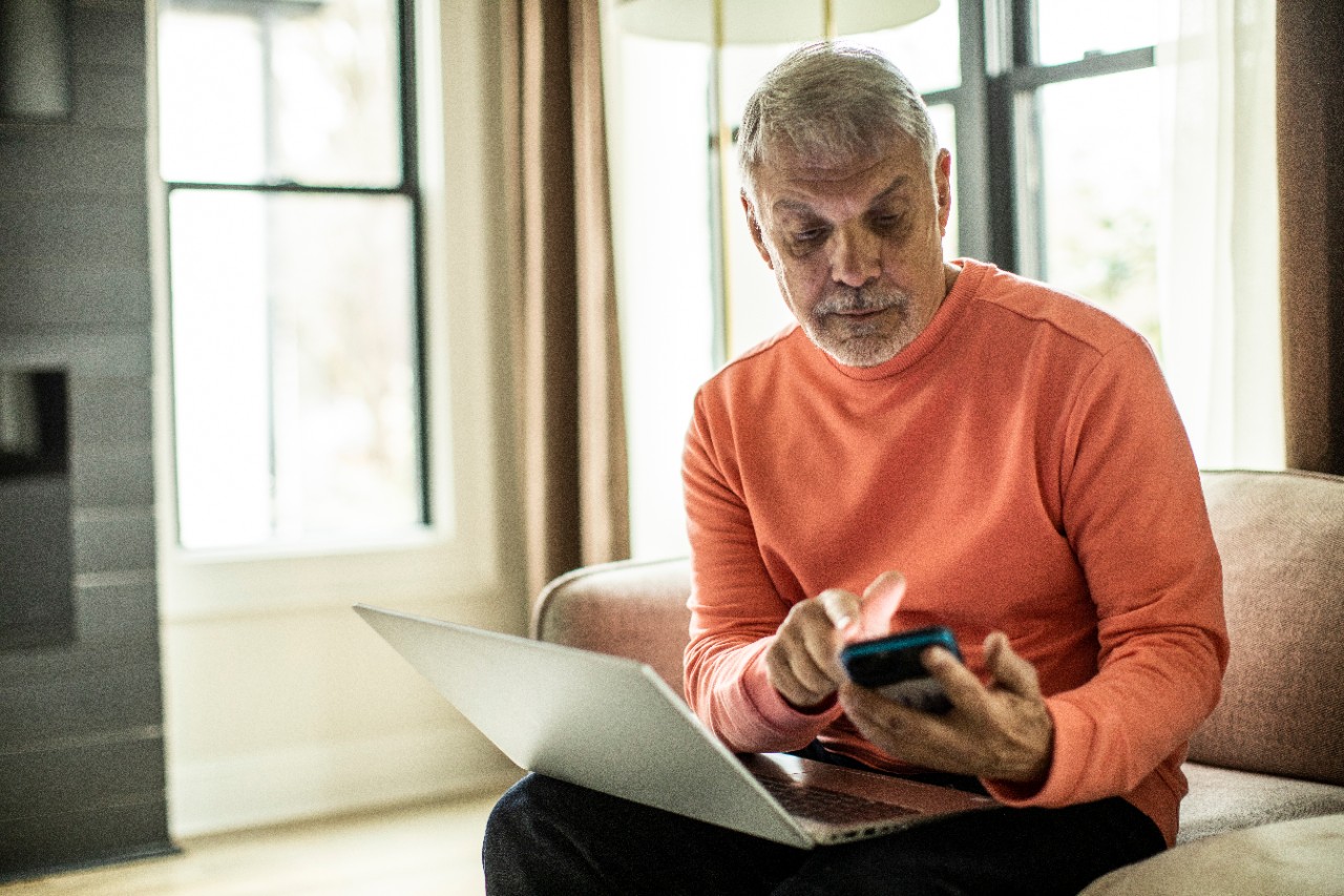 Man researching NatWest ISAs on laptop and mobile