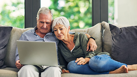 mature couple sitting on a sofa looking at a laptop